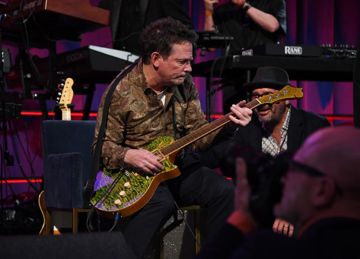 Michael J. Fox plays guitar onstage. 