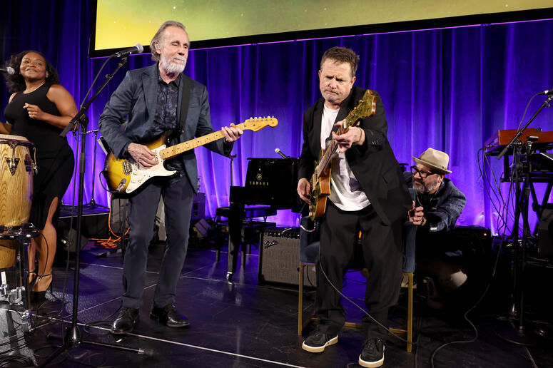 Jackson Browne and Michael J. Fox perform onstage. 