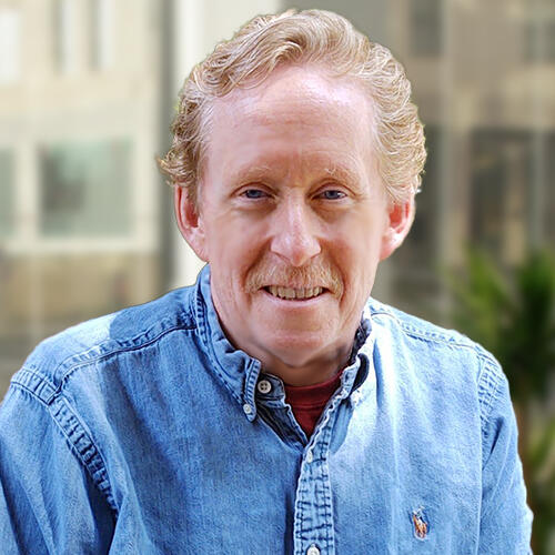 A man smiles outdoors.