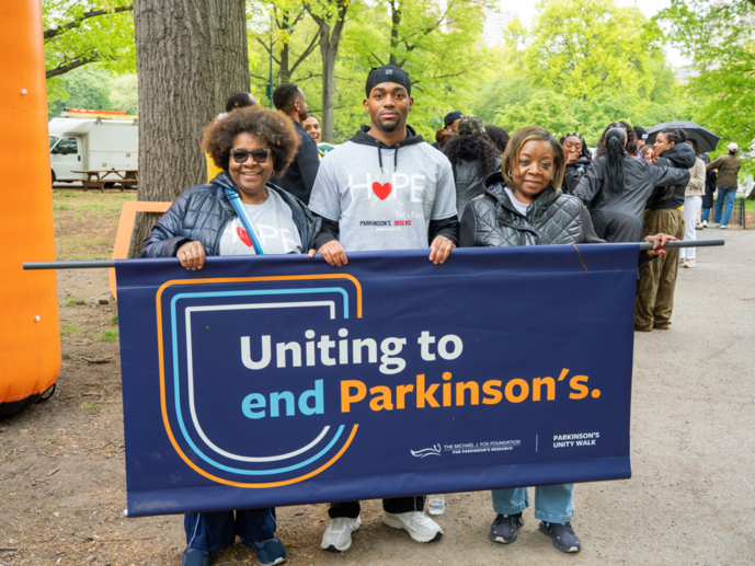 A group holds up a sign that says "Uniting to end Parkinson's."