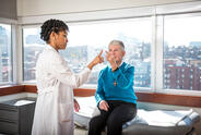 A doctor checks a patient in an office overlooking a city.
