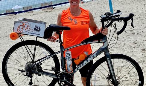 Bethany Richards holding bike on the beach.
