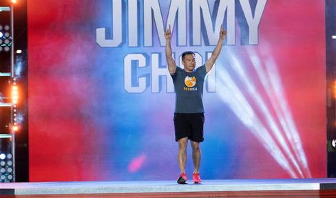 Jimmy Choi with his hands in the air cheering, while walking on to the American Ninja Warrior course.