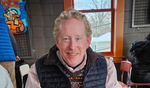 A man smiles indoors at a restaurant.