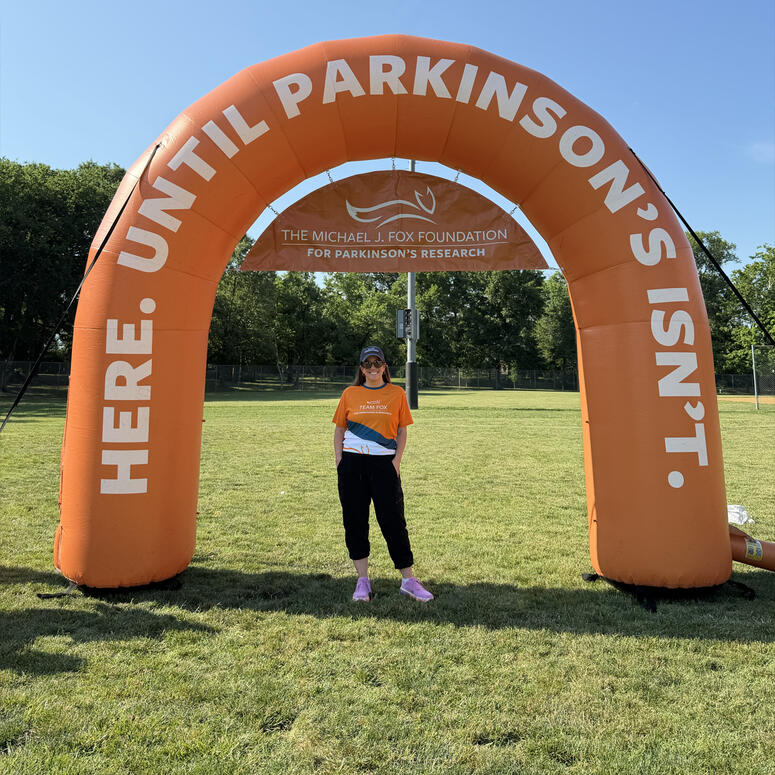 Allie Signorelli stands beneath an inflated orange arch at a MJFF event