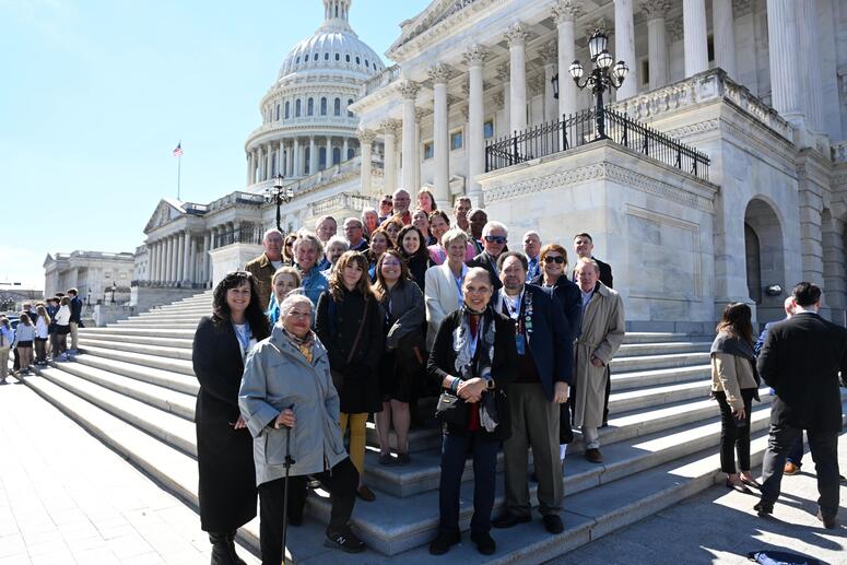 a group of people stand on the steps outside a capital building