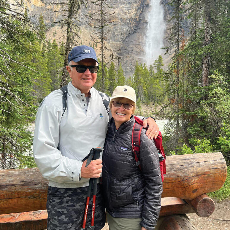 Donna Krenecki and her husband standing outdoors near a waterfall