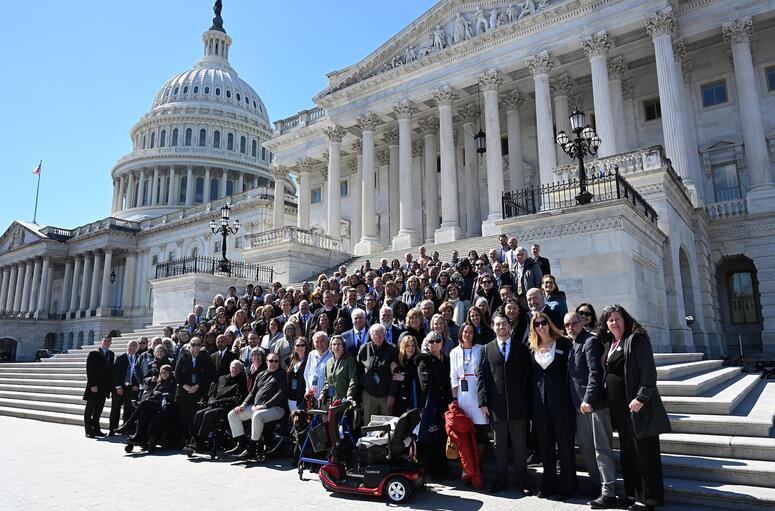 A large group of people pose on the steps of a capital building