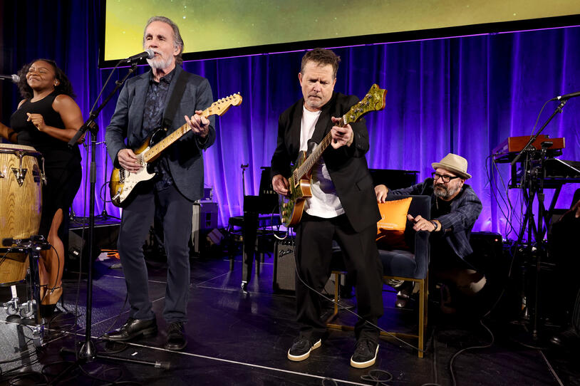 Jackson Browne and Michael J. Fox perform onstage. 