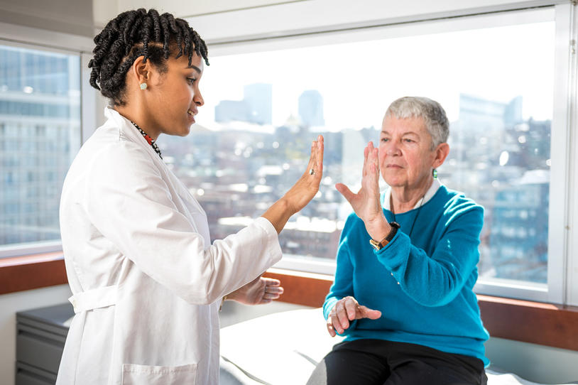 Female doctor performing a Parkinson's test with female patient.