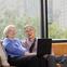 A seated couple smile while sharing a laptop.