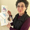 A woman holds up her illustrations.