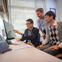 Three men in an office looking at a computer screen.