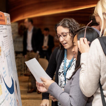 Three researchers looking at a presentation board at a conference